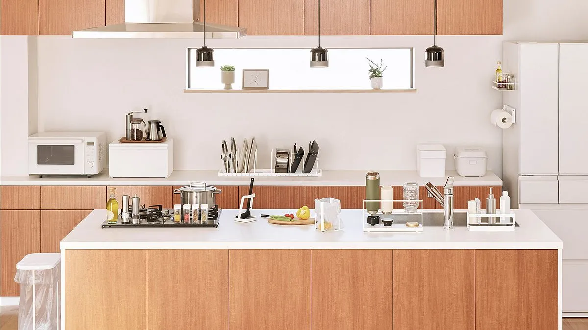 A kitchen from the showroom shoot: wood cabinets, a white island with Yamazaki racks, stands and a knife block set out on it, pendant lights above.